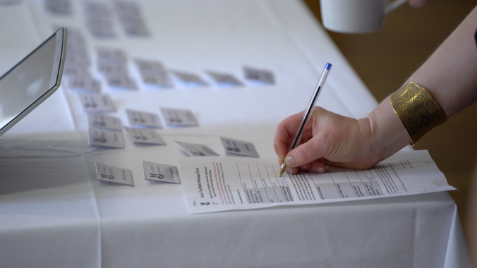 Close up of sign-in sheet with a hand at the Symposium, A la Ronde, Devon.